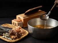 Traditional Japanese dashi ingredients including kombu, katsuobushi, niboshi, and dried shiitake with a pot of freshly made dashi broth