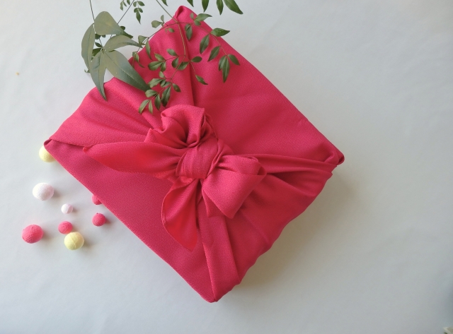Japanese gift wrapped in bright pink furoshiki cloth, symbolizing traditional presentation culture