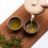 Japanese green tea being poured from a teapot into two teacups