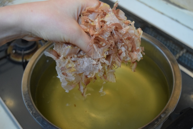 katsuobushi flakes being added to hot water to make Japanese dashi broth