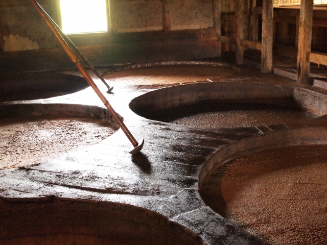 Traditional fermentation room with multiple large vats inside a Japanese brewery.