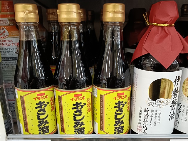 Bottles of sashimi soy sauce and tamari displayed on a shelf in a Japanese supermarket.