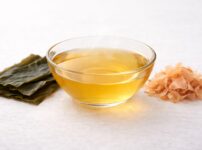 kombu seaweed and katsuobushi bonito flakes next to a bowl of clear dashi broth