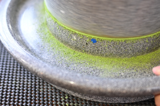 Close-up of stone mill grinding matcha into fine powder