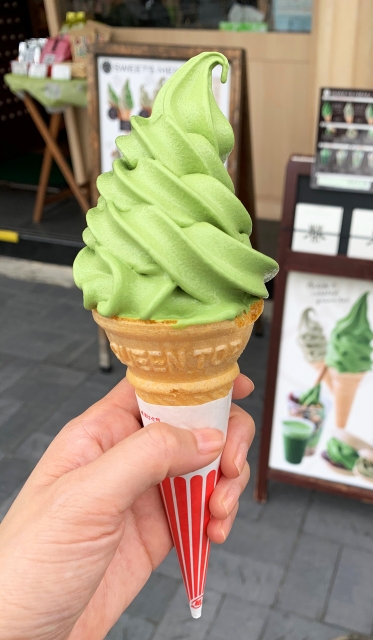 Matcha soft serve ice cream held outdoors with vivid green color
