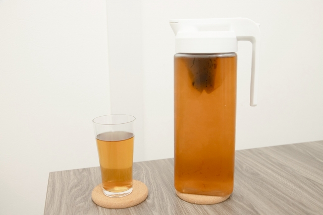 A pitcher of mugicha barley tea with a tea bag, served cold in a glass