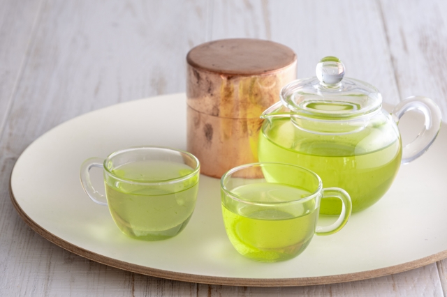 Japanese green tea served casually with a glass teapot, cups, and tea canist
