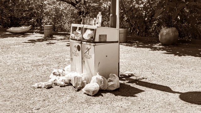 Overflowing public trash bin with garbage scattered around it