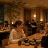 Foreign travelers enjoying a relaxed conversation in a modern Japanese restaurant while other diners quietly share the space, creating a calm and comfortable atmosphere