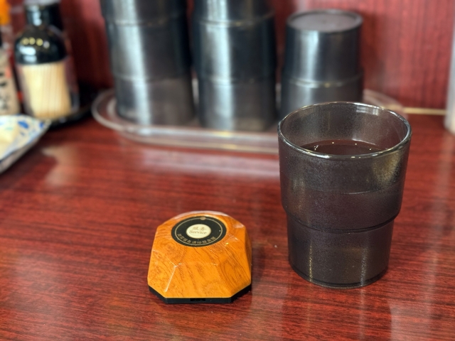 Small restaurant call button placed beside a water glass on a Japanese restaurant table