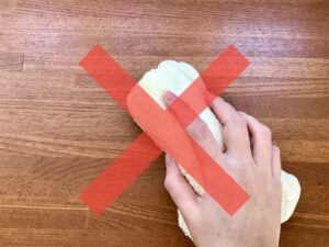 Hand using an oshibori to wipe a table with a red cross symbol