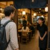 Japanese restaurant staff welcoming a customer with “Irasshaimase” at the entrance of a traditional izakaya