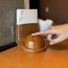 Finger pressing a wooden call button on the table inside a Japanese restaurant