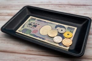 Cash and coins placed inside a payment tray used at a Japanese register counter