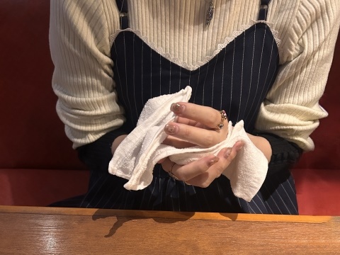 Person wiping hands with an oshibori towel