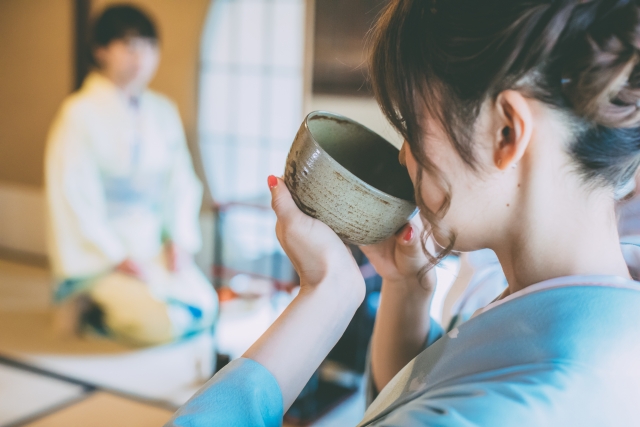 Woman tasting traditional matcha from a tea bowl during a Japanese tea gathering