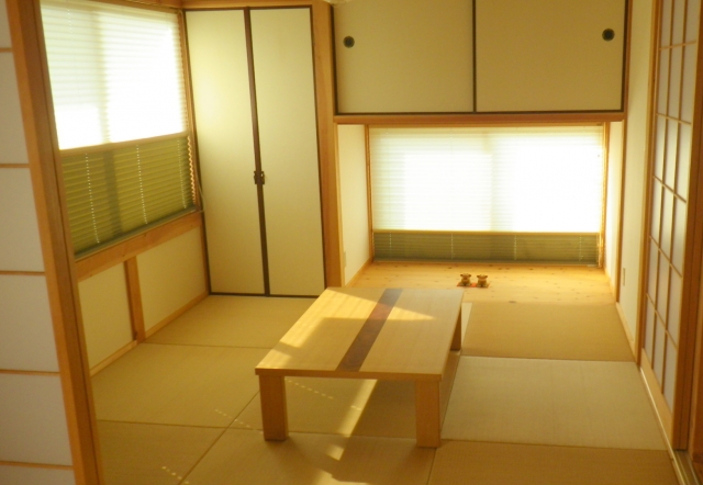 A traditional washitsu in a Japanese home featuring tatami flooring, shoji screens, fusuma sliding doors, and a low table arranged for flexible daily use