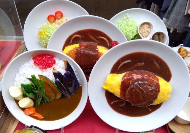 Japanese food replica display featuring realistic omurice, curry rice, and salad models arranged in a restaurant showcase window