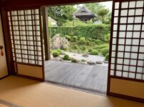 Interior view of a traditional Japanese home with tatami flooring, shoji doors, and an engawa overlooking a garden