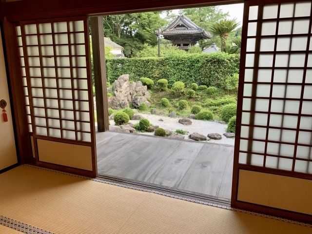 Interior view of a traditional Japanese home with tatami flooring, shoji doors, and an engawa overlooking a garden