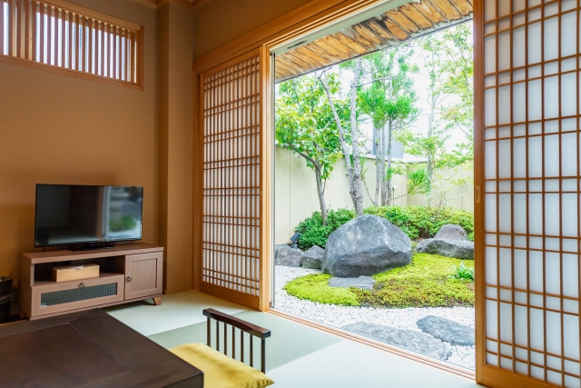 A modern washitsu with tatami flooring, shoji screens, and a garden view, showing how Japanese homes use natural light, airflow, and flexible boundaries for comfort