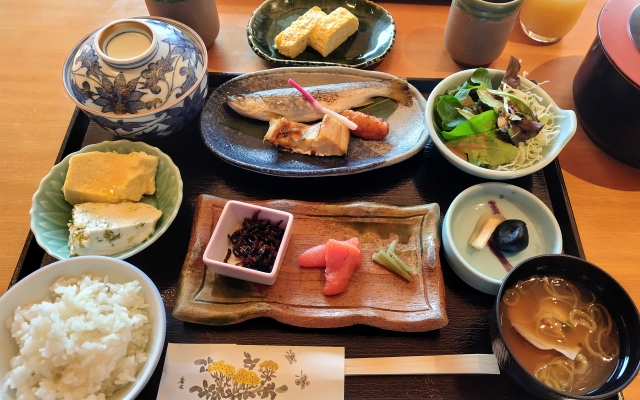 A carefully arranged ryokan breakfast with rice, miso soup, grilled fish, tamagoyaki, small side dishes, and salad.