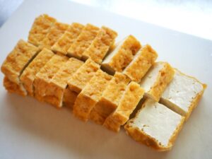Sliced atsuage showing its golden fried exterior and thick white tofu center.