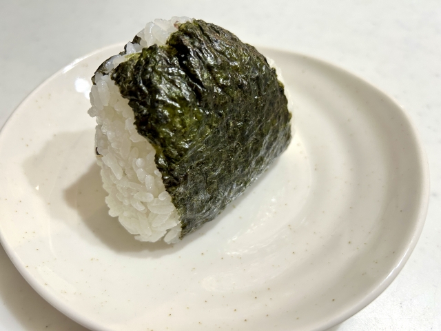 A simple homemade onigiri rice ball with a slightly uneven handmade shape.