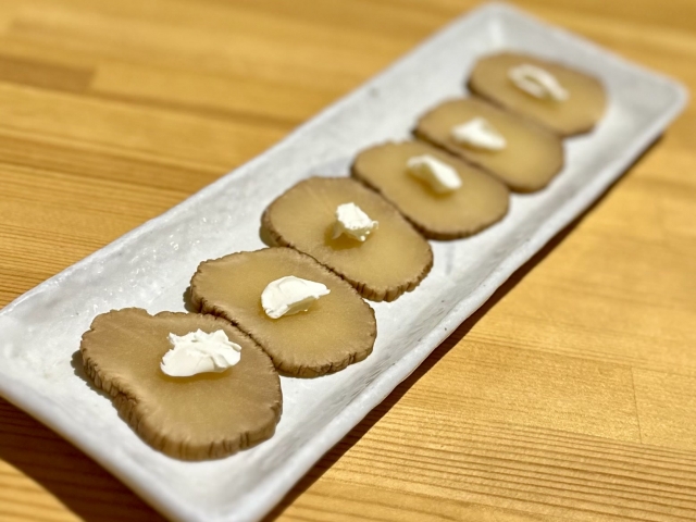 Slices of Akita iburigakko topped with cream cheese, a modern way to serve smoked daikon pickles.
