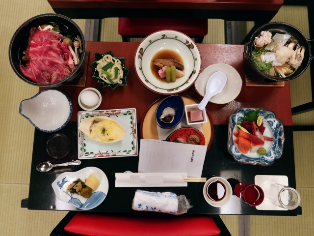 A traditional ryokan dinner with many small dishes, rice, soup, and regional specialties, illustrating an expanded form of the organizing principles behind ichiju sansai.