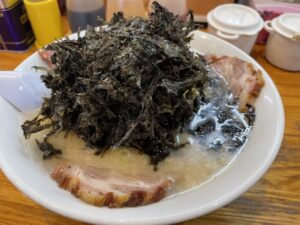 A bowl of ramen topped with loose iwa nori, showing its rough texture and strong presence in a hot noodle dish.