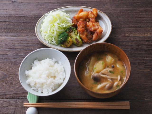 A simple home-style ichiju issai meal with rice, miso soup, and a single chicken dish with shredded cabbage, illustrating a simplified Japanese meal structure.