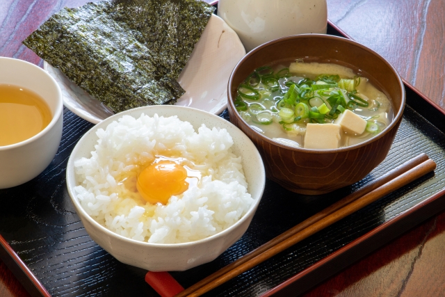 A simple Japanese breakfast with rice, raw egg, miso soup, tea, and a small plate of nori, showing how seaweed quietly supports an everyday meal.