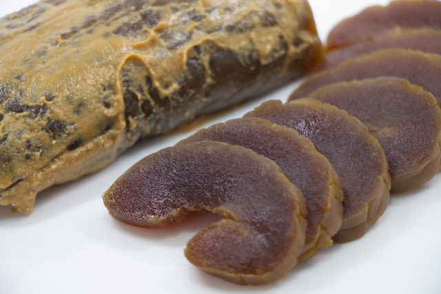Dark slices of narazuke beside vegetables coated in sake lees, showing the pickle’s deep color and transformation.