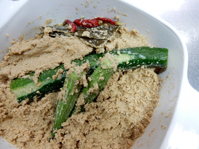 Cucumbers buried in a fermented rice bran bed, showing how nukazuke is made in a household nukadoko.