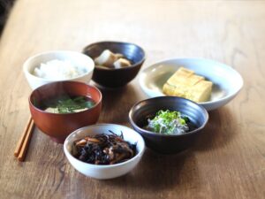 A Japanese breakfast with rice, miso soup, tamagoyaki, cold tofu, hijiki, and several small side dishes.