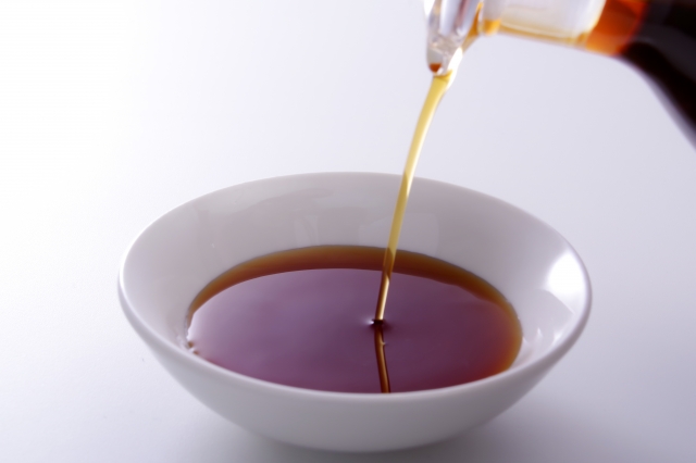 Japanese soy sauce being poured into a white bowl, showing its clear reddish-brown color.