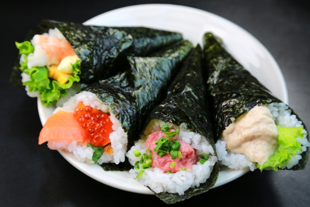 Homemade hand roll sushi wrapped in roasted nori, showing one common way yaki nori is used with rice and fillings in Japan.