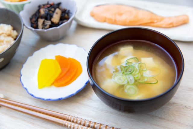 A small serving of Japanese pickles beside miso soup, rice, and other mild side dishes, showing how tsukemono support the meal.