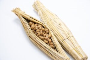 Traditional Japanese natto wrapped in rice straw, shown with the fermented soybeans inside.