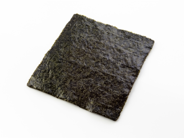 Sheets of roasted nori seaweed on a white background, showing their thin shape and dark textured