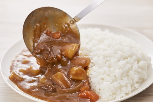 A spoonful of thick Japanese curry being served beside white rice, showing the sauce’s rich, smooth texture
