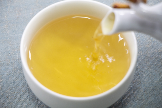 Pale yellow-green kukicha tea being poured into a cup