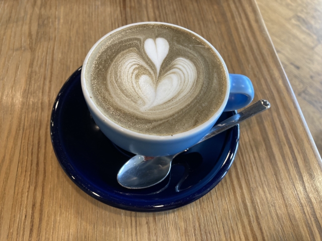 Hojicha latte with milk foam served in a blue cup