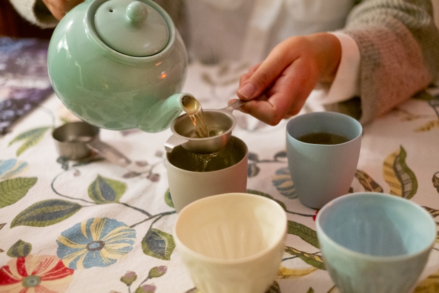 Konacha being poured through a fine tea strainer into a teacup