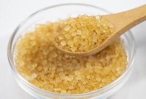 Large amber-colored chūzarame sugar crystals on a wooden spoon above a glass bowl
