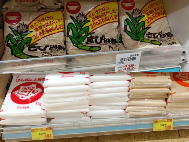 Japanese supermarket shelf showing jōhakutō, sanontō, and kibi sugar in different package sizes with price labels