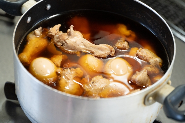 Chicken drumettes and boiled eggs simmering in a pot with vinegar, soy sauce, and other seasonings.