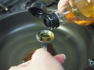 Seasoning being measured over a frying pan to adjust the sauce in Japanese cooking.