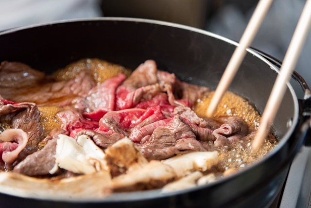 Thinly sliced beef simmering in a sukiyaki pan with mushrooms and sweet-savory sauce